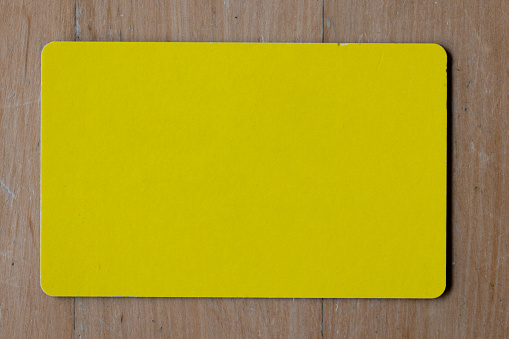 Blank yellow card on wooden table