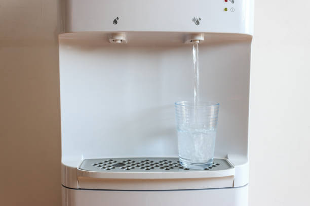 el agua fría fluye desde el dispensador de agua hasta el vidrio en el hogar. concepto de agua saludable en verano. - refrigeradora de agua fotografías e imágenes de stock