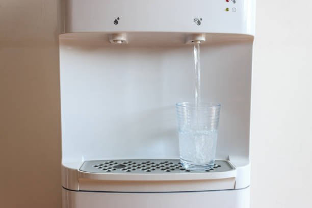 冷たい水は家庭のガラスに水ディスペンサーから流れています。夏の健康的な水の概念。 - water cooler ストックフォトと画像