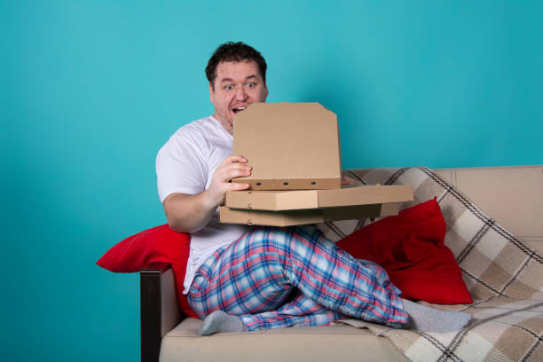 istock Funny fat man eating pizza and watching tv. 1337021482