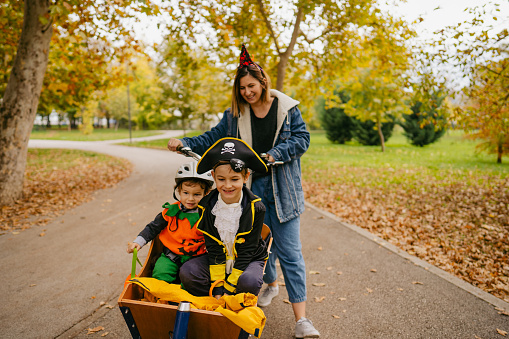 Photo of a costumed family going together by cargo bike to collect some candies for the Halloween