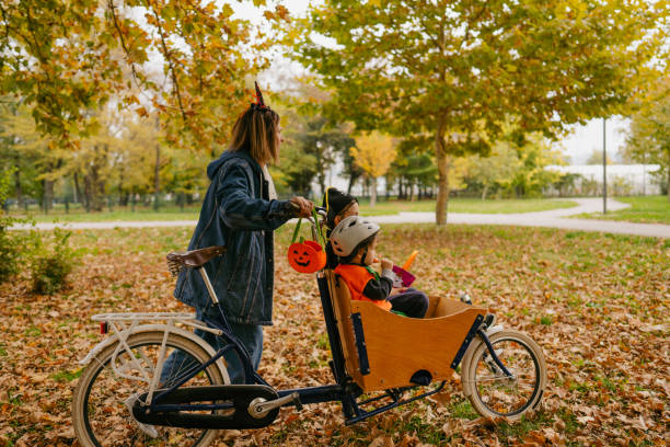 costumed family going to collect candies for the halloween - parents children cargo bike bildbanksfoton och bilder