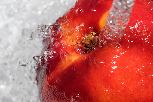 Ripe sweet nectarine is washed under a stream of clean water close-up macro photography