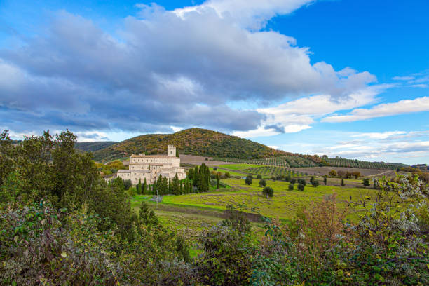 Magnificent Italy. Tuscany. The magnificent snow-white abbey of Sant Antimo among green grassy hills and slender cypress trees. Wonderful medieval architecture.