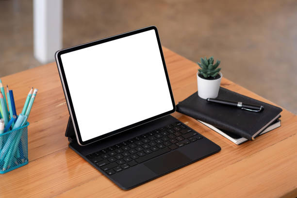 istock Tablet blank white screen with work equipment placed at wooden office desk. Mock up. 1337029387