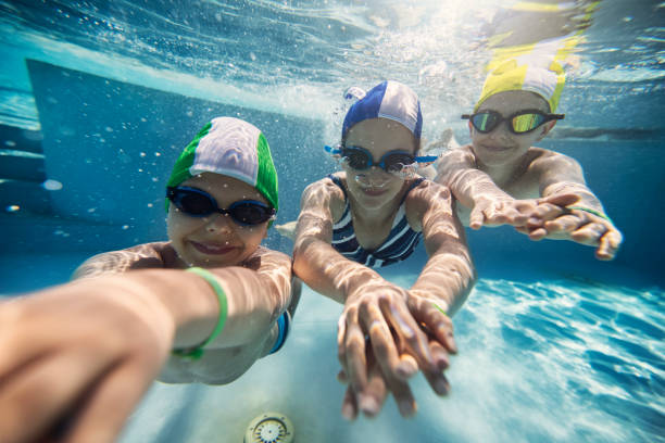 수영장에서 수중으로 수영하는 행복한 세 아이 - 수영모자 뉴스 사진 이미지