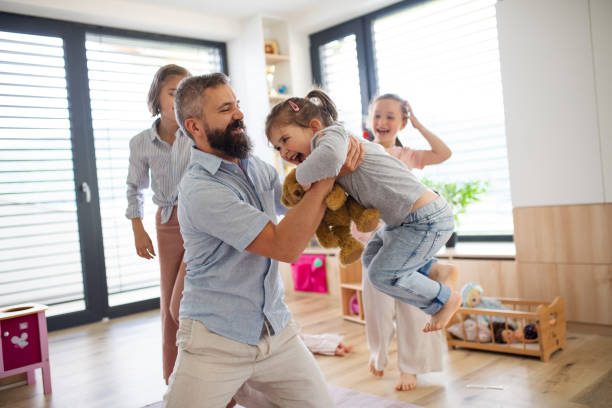 istock Father with three daughters indoors at home, playing on floor. 1337045068