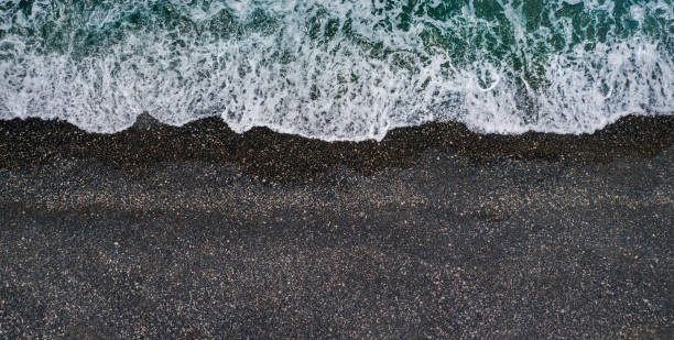 Sea waves breaking on black sand beach, aerial background