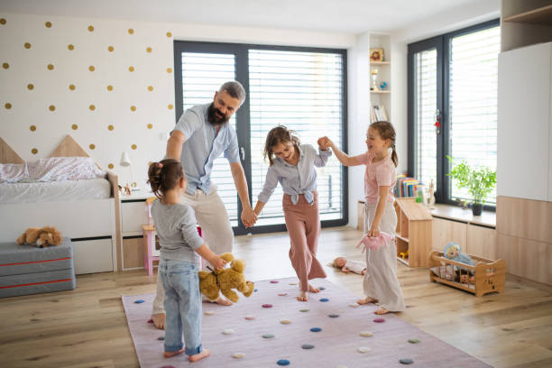 istock Father with three daughters indoors at home, playing and holding hands. 1337045620