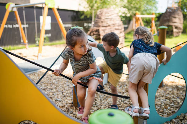 gruppe von kleinen kindergartenkindern, die draußen auf dem spielplatz spielen. - kinderspielplatz stock-fotos und bilder