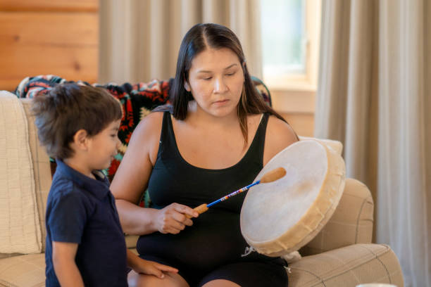 indigenous mother playing the drums for her son at home - etnicidade de índio imagens e fotografias de stock