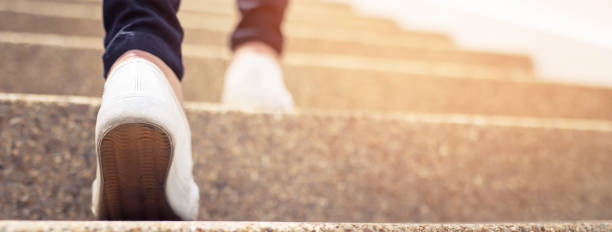 scala. chiudi le gambe e le scarpe scarpe da ginnastica di una giovane donna una persona che cammina salendo le scale nella città moderna, successo, crescere. - gradino singolo foto e immagini stock