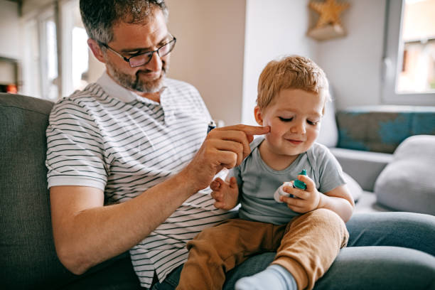 Father carefully applying medical ointmen on his son face