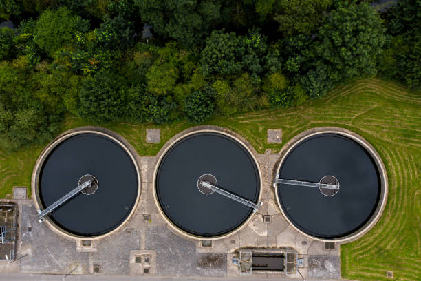 Aerial view of a row of sewage tanks at a water treatment plant to purify drinking water￼ Aerial view of the tanks of a UK sewage and water treatment plant enabling the discharge and re-use of waste water and re-use of waste water sewage stock pictures, royalty-free photos & images