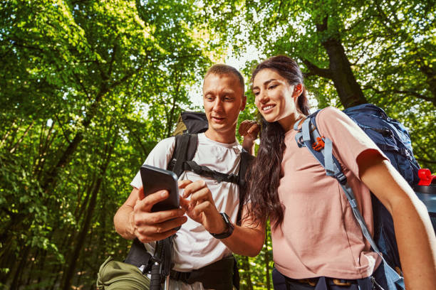 istock Happy tourists using smartphone in green forest 1337058666