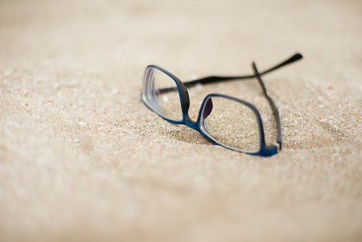 Blue rimmed glasses on the sand.