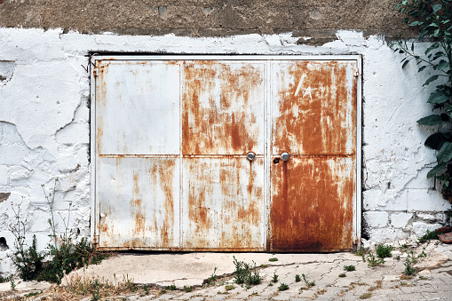 Old metal rusty gray warehouse door.