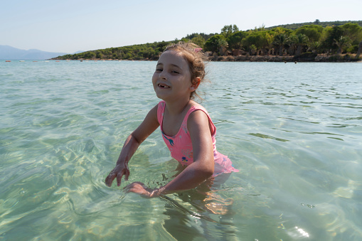 Small girl is jumping and swimming on the waves in the sea