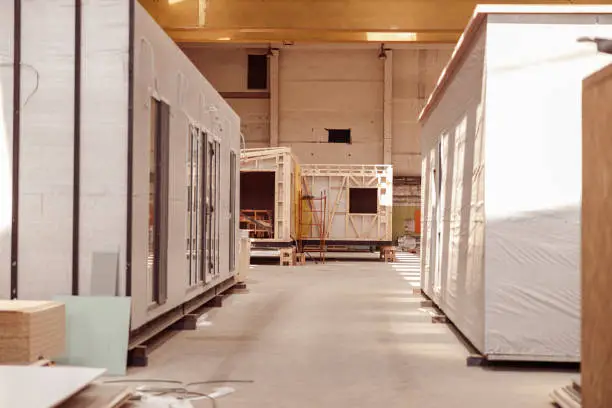 Building with concrete floor, construction materials and two mobile cabins with panel siding and glass doors