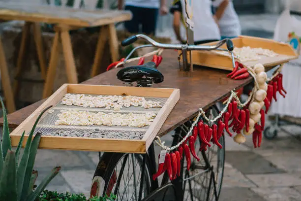 Fresh orecchiette or orecchietta, made with durum wheat and water, drying on a wooden board on a bike with red chili and garlic, handmade pasta typical of Puglia or Apulia, a region of Southern Italy