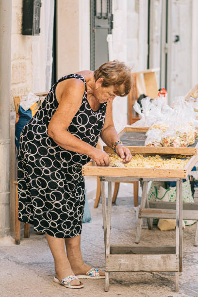 donna del posto che si prepara nella via del centro storico di bari orecchiette o orecchietta - orecchiette foto e immagini stock