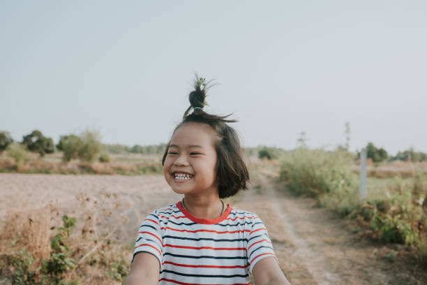 Happy face of Thai local girl along rice farm for getting fresh air - stock photo Thai lovely girl smile while cycling on rural road along farm to see her father working. topknot stock pictures, royalty-free photos & images