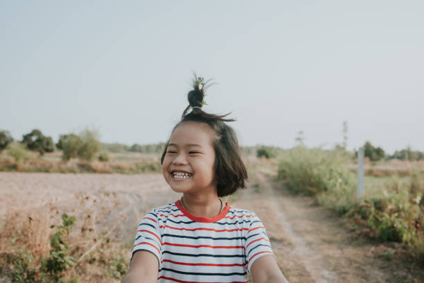 rosto feliz da garota tailandesa local ao longo da fazenda de arroz para obter ar fresco - foto de estoque - fun simplicity children only color image - fotografias e filmes do acervo