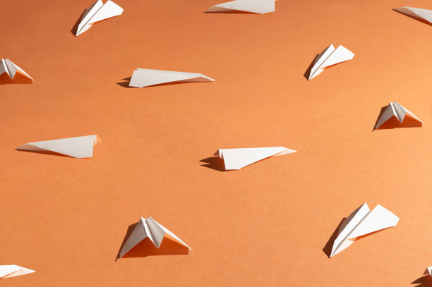 istock White paper airplanes on pastel background. Simple origami 1337072957