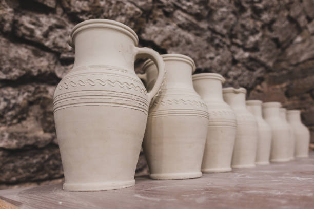 Clay pots stand on a shelf in a row.