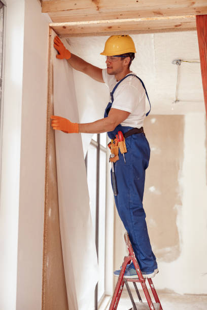 istock Handsome young man hanging wallpaper on the wall 1337074540
