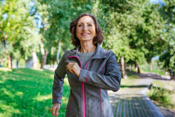 mulher feliz e madura correndo no parque ao ar livre - senior adult running jogging senior women - fotografias e filmes do acervo