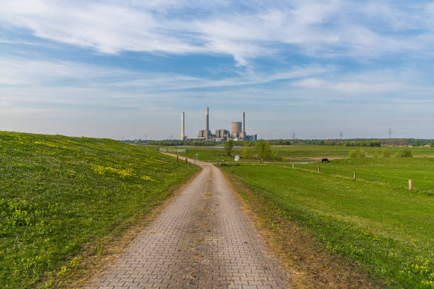 View towards the River Rhine in Orsoy, Germany Rheinberg, North Rhine-Westphalia, Germany - April 16, 2020: View at the River Rhine in Orsoy, with the Voerde power station in the background rheinberg illumination stock pictures, royalty-free photos & images