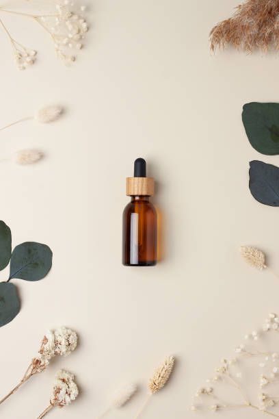 istock Cosmetic bottle with flowers and eucalyptus on pastel beige background. Flat lay 1337079334