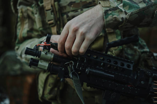 porträt eines airsoft-spielers in professioneller ausrüstung lädt eine waffe mit kugeln in den wald. soldat mit waffen im krieg - airsoft gun stock-fotos und bilder