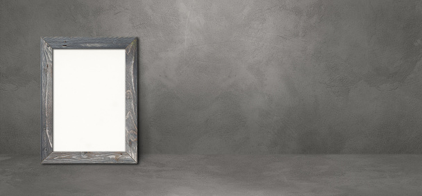 Wooden picture frame leaning on a dark concrete wall. Blank mockup template. Horizontal banner