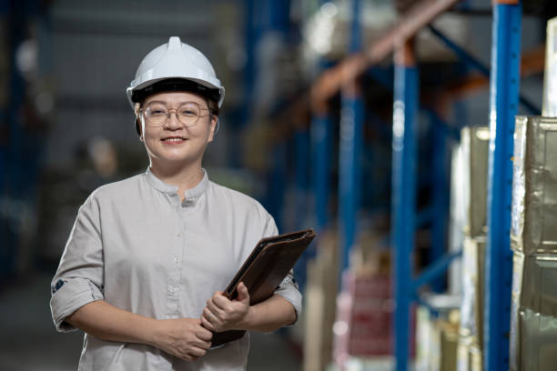 istock Asian Chinese management at warehouse with white hardhat holding digital tablet smiling looking at camera 1337083836