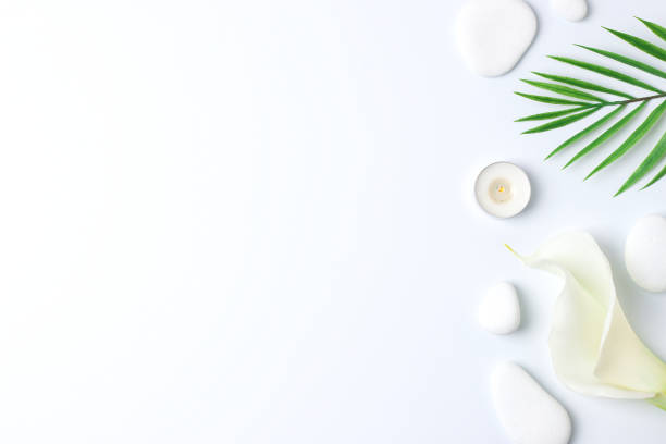 istock Spa background with white stones, candles, palm leaf and white flower on white. Flat lay,copy space 1337085358