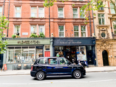 School of Chocolate in Seven Dials, London, with a black cab driving past and people visible in the background