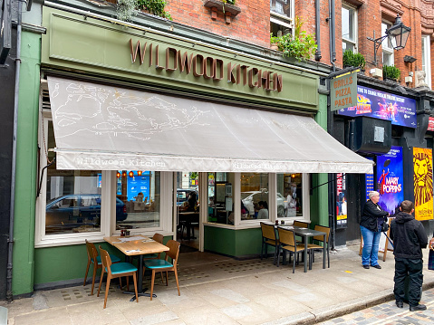 Wildwood Kitchen Pizza Kitchen on Shaftesbury Avenue in Seven Dials, London, with people and theatre posters visible.