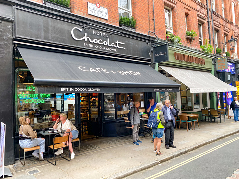 People walking past Hotel Chocolat on Monmouth Street in Seven Dials, London. This is an upmarket chocolate shop.