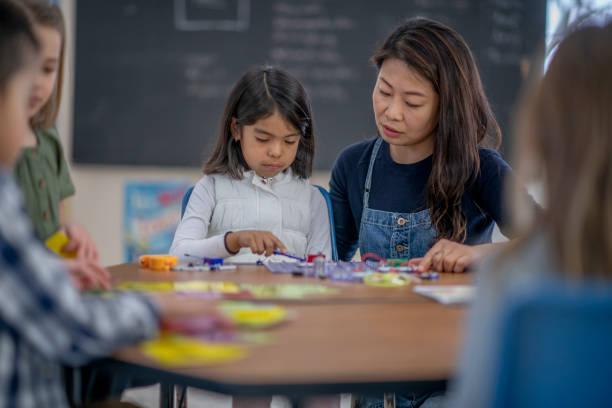 istock Korean female elementary school teacher helping her student in class 1337091119