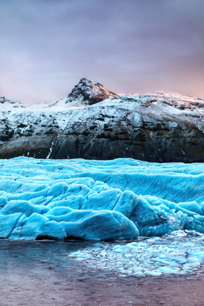 snow covered mountain and blue glacial ice of the svinafellsjokul glacier in southeast iceland. this is the largest ice cap in europe. winter scene at dusk. - skaftafell national park 個照片及圖片檔