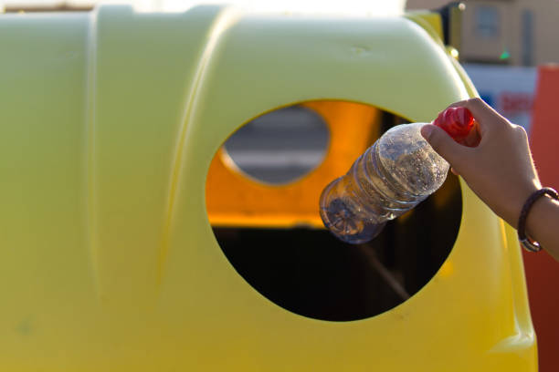 istock White hand depositing a plastic bottle in the recycling container 1337093860