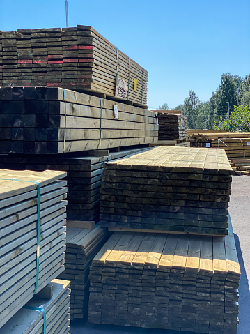 Piles of pressure treated timber. For sale outside hardware store warehouse.