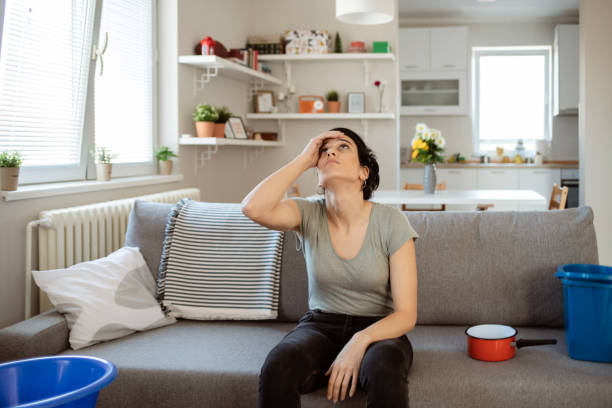 mujer recogiendo agua con fugas del techo - roof leak fotografías e imágenes de stock