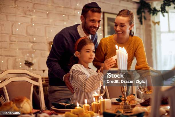Happy Jewish Family Lightning The Menorah Before A Meal At Dining Table Stock Photo - Download Image Now
