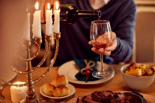 close-up do homem derramando vinho kosher na mesa de jantar durante hanukkah. - kosher wine - fotografias e filmes do acervo