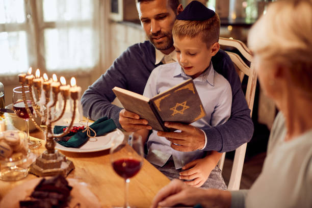 ハヌカの間にダイニングテーブルでタナクを読む小さなユダヤ人の少年と彼の父親。 - judaism ストックフォトと画像