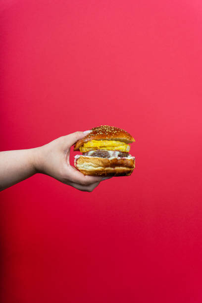 istock human hand holding tasty hamburger cheeseburger burger isolated on red background 1337101730