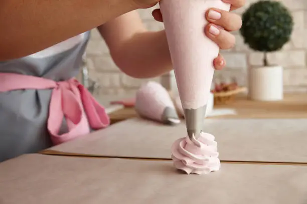 Confectioner making marshmallow desserts with pastry bag, close up view